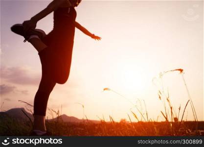 sunset with sport woman runner stretching muscle after run