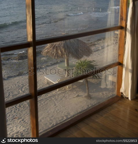Sunshades with chairs on the beach viewed from window, Utopia Village, Utila, Bay Islands, Honduras