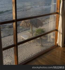 Sunshades with chairs on the beach viewed from window, Utopia Village, Utila, Bay Islands, Honduras