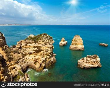 Sunshine above rock formations along coastline (Ponta da Piedade, Lagos, Algarve, Portugal). Peoples unrecognizable.