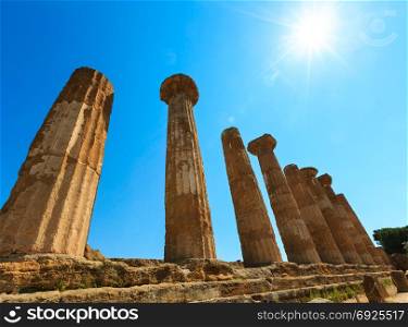 Sunshine above ruined Temple of Heracles columns in famous ancient Valley of Temples, Agrigento, Sicily, Italy. UNESCO World Heritage Site. Some lens flares from sunshine available