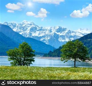 Sunshiny Reschensee ( or Lake Reschen) summer landscape with blossoming meadow and blue cloudy sky (Italy)