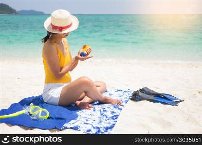 Suntan lotion Smiling young woman on beach applying sun block cream from a plastic container.. Suntan lotion Smiling young woman on beach applying sun block cr