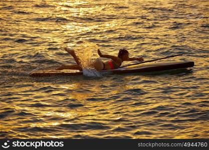 SUP Stand up Surf girl swimming lying on board at sunset