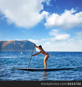 SUP Stand up Surf girl with paddle in a blue ocean sea