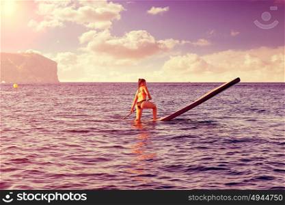 SUP Stand up Surf girl with paddle in a blue ocean sea