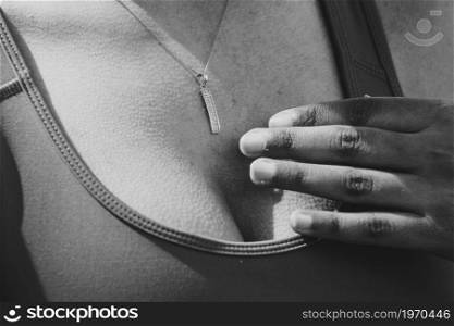 Super close up of a jewelry in black and white in the chest of a woman