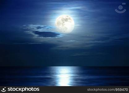 Super full moon and cloud in the blue sky above the ocean horizon at midnight, moonlight reflect the water surface and wave, Beautiful nature landscape view at night scene of the sea for background. View at night scene of the sea