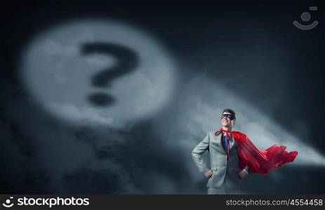 Super hero in search light. Young smiling super businessman in mask and cape at night