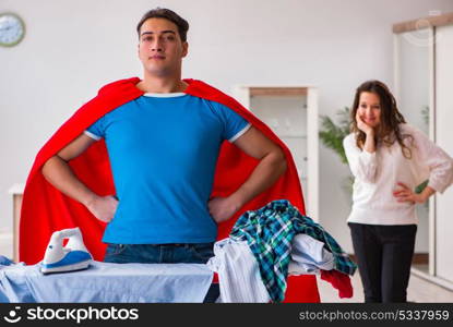 Super hero man husband ironing at home helping his wife