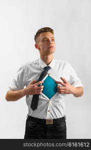 super hero suit of business man. Young businessman showing suit of super hero with copy space under his shirt and tie on gray background