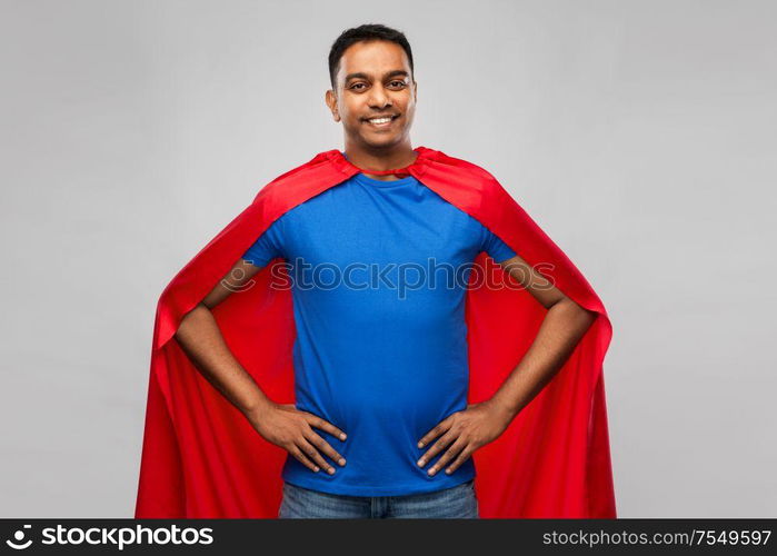 super power and people concept - happy smiling indian man in red superhero cape with arms on hips over grey background. happy smiling indian man in red superhero cape