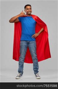 super power and people concept - happy smiling indian man in red superhero cape making phone call gesture over grey background. indian man in superhero cape making call gesture