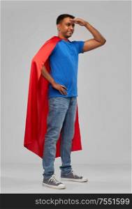 super power and people concept - happy smiling indian man in red superhero cape looking far away over grey background. indian man in red superhero cape looking far away