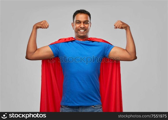 super power and people concept - indian man in red superhero cape showing his muscles over grey background. indian man in superhero cape showing his power