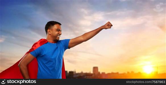 super power and people concept - indian man in red superhero cape making winning gesture over sunset in city background. indian man in superhero cape makes winning gesture