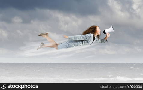 Super woman. Young businesswoman with megaphone flying high in sky