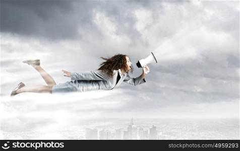 Super woman. Young businesswoman with megaphone flying high in sky