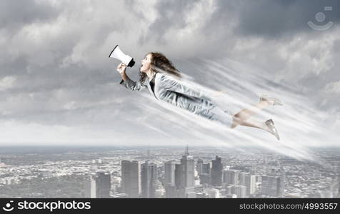 Super woman. Young businesswoman with megaphone flying high in sky