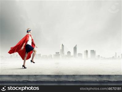 Super woman. Young confident woman in red cape and mask
