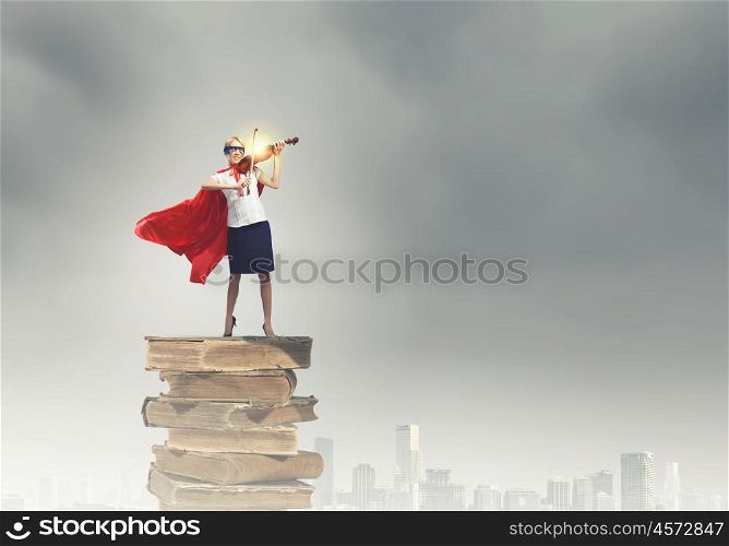 Super woman. Young confident woman in red cape and mask playing violin