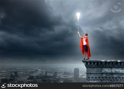 Super woman. Young woman in super hero costume with bulb balloon in hand