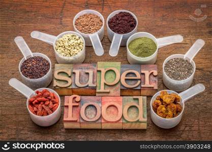superfood abstract (wheatgrass, acai berry, goji berry, falx seed,chia seed,goldenberry,hemp seed, quinoa grain) - a set of measuring scoops with la letterpress text against rustic wood
