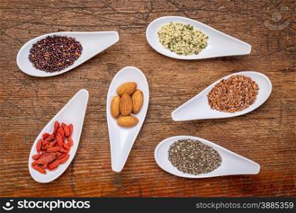 superfood grain, seed, berry, and nuts abstract - top view of spoon bowls against rustic wood