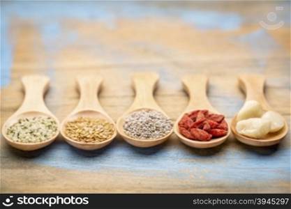superfood (hemp seeds, golden flax seeds, chai seeds, goji berry, macadamaia nuts) on wooden spoons - abstract with a shallow depth of field