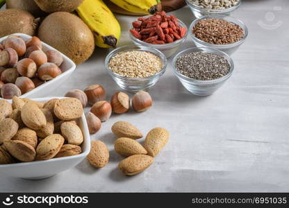 Superfoods on a gray background with copy space. Nuts, beans, greens and seeds. Healthy vegan food.