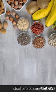 Superfoods on a gray background with copy space. Nuts, beans, greens and seeds. Healthy vegan food.