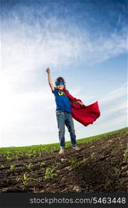 Superhero kid jumping against dramatic blue sky background