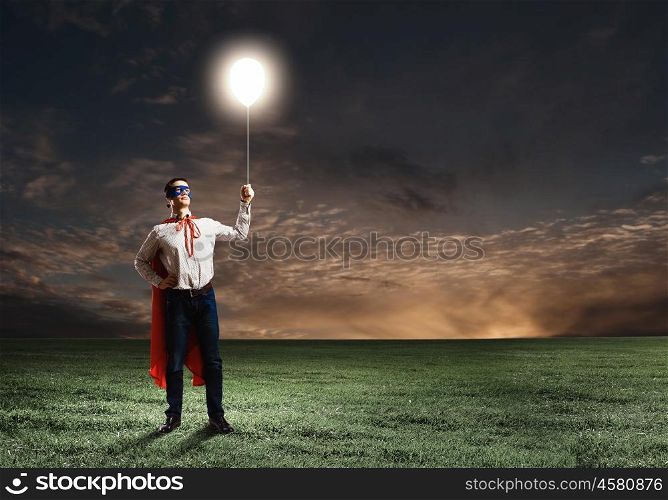 Superhero with balloon. Young confident superman in mask and cape
