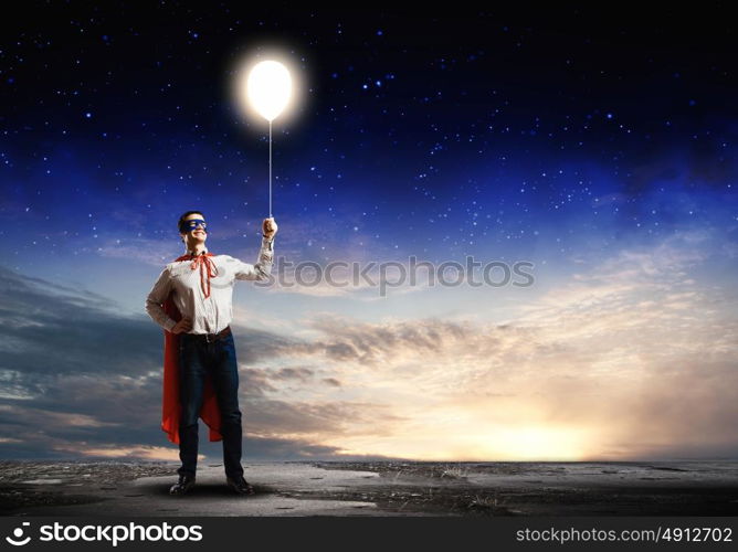 Superhero with balloon. Young confident superman in mask and cape