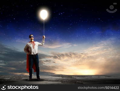 Superhero with balloon. Young confident superman in mask and cape