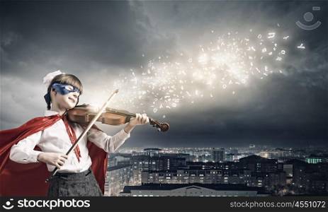Superkid playing violin. Cute girl of school in superhero costume playing violin