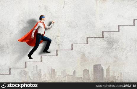 Superman on ladder. Young superman walking up the stair case