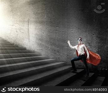 Superman on ladder. Young superman walking up the stair case