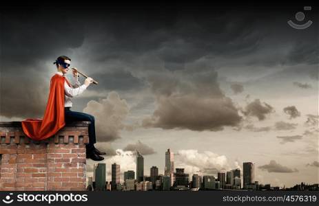 Superman on roof. Superman in cape and mask sitting on top of building