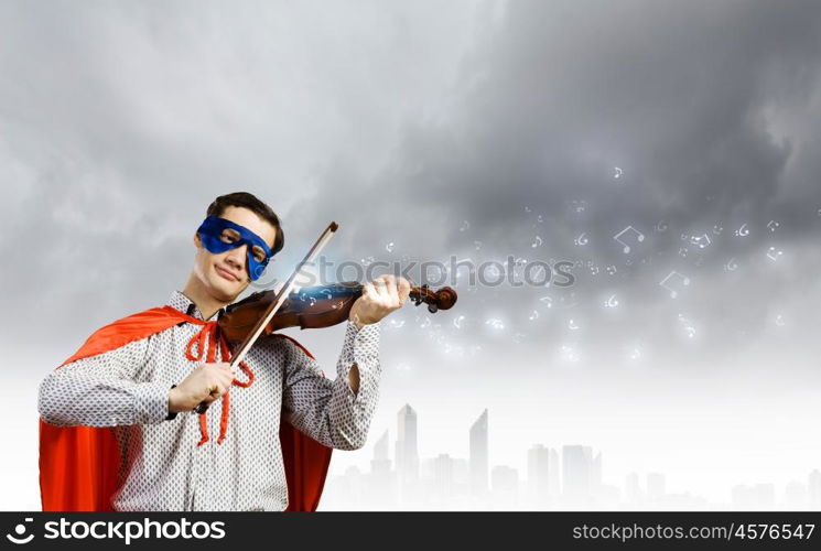 Superman playing violin. Young man in superhero costume playing violin