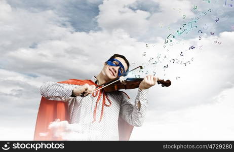 Superman playing violin. Young man in superhero costume playing violin