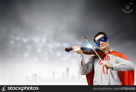 Superman playing violin. Young man in superhero costume playing violin