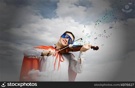 Superman playing violin. Young man in superhero costume playing violin