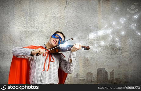 Superman playing violin. Young man in superhero costume playing violin