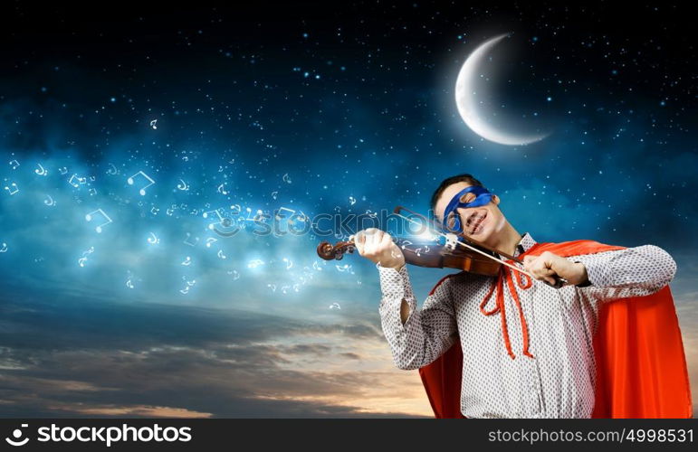 Superman playing violin. Young man in superhero costume playing violin