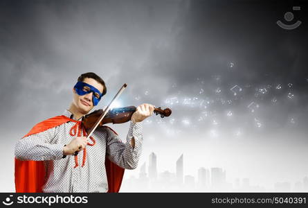 Superman playing violin. Young man in superhero costume playing violin