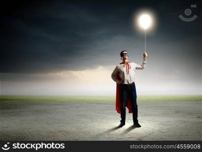 Superman with balloon. Young man in superhero costume holding balloon in hand