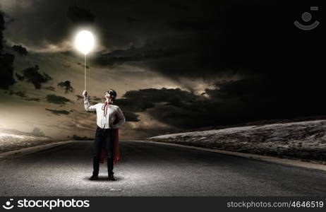 Superman with balloon. Young man in superhero costume holding balloon in hand