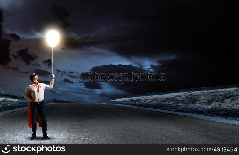 Superman with balloon. Young man in superhero costume holding balloon in hand