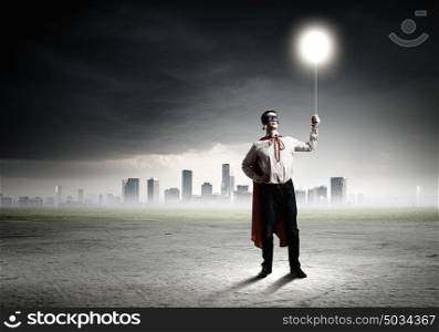 Superman with balloon. Young man in superhero costume holding balloon in hand